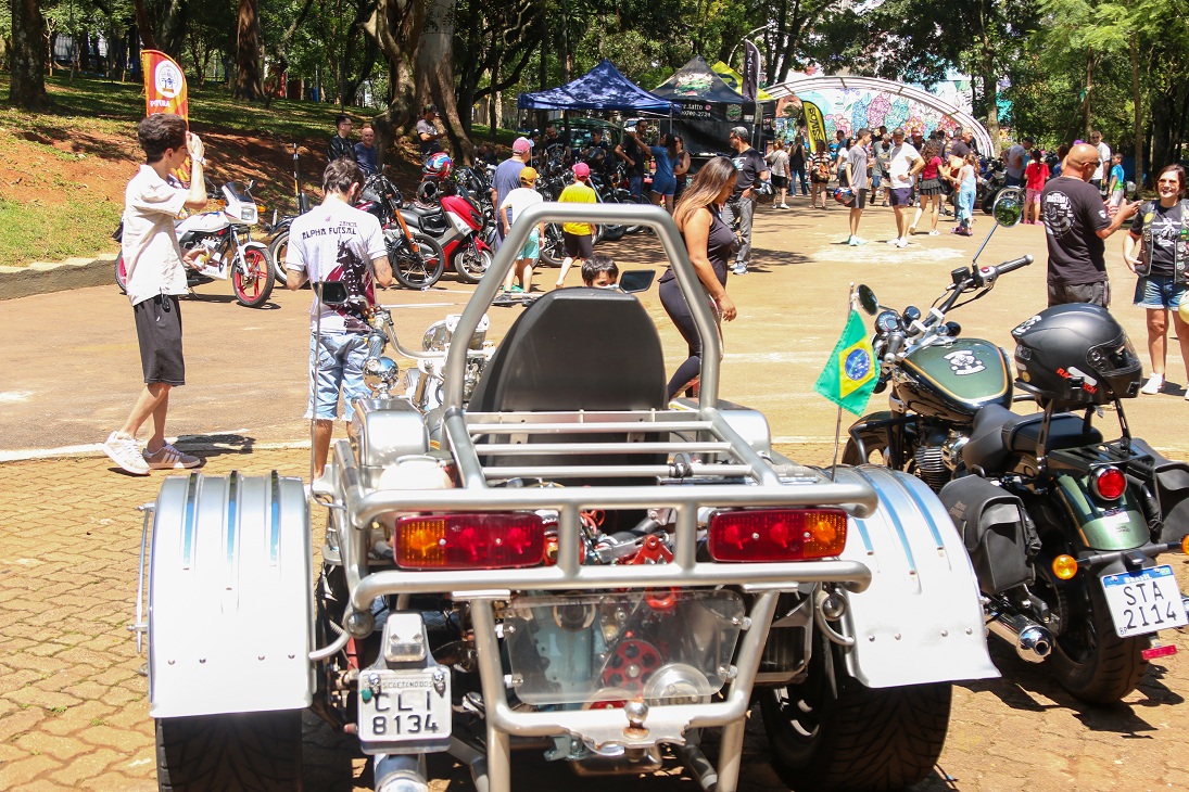 Visitantes observam triciclo e motos expostos no Bosque do Povo